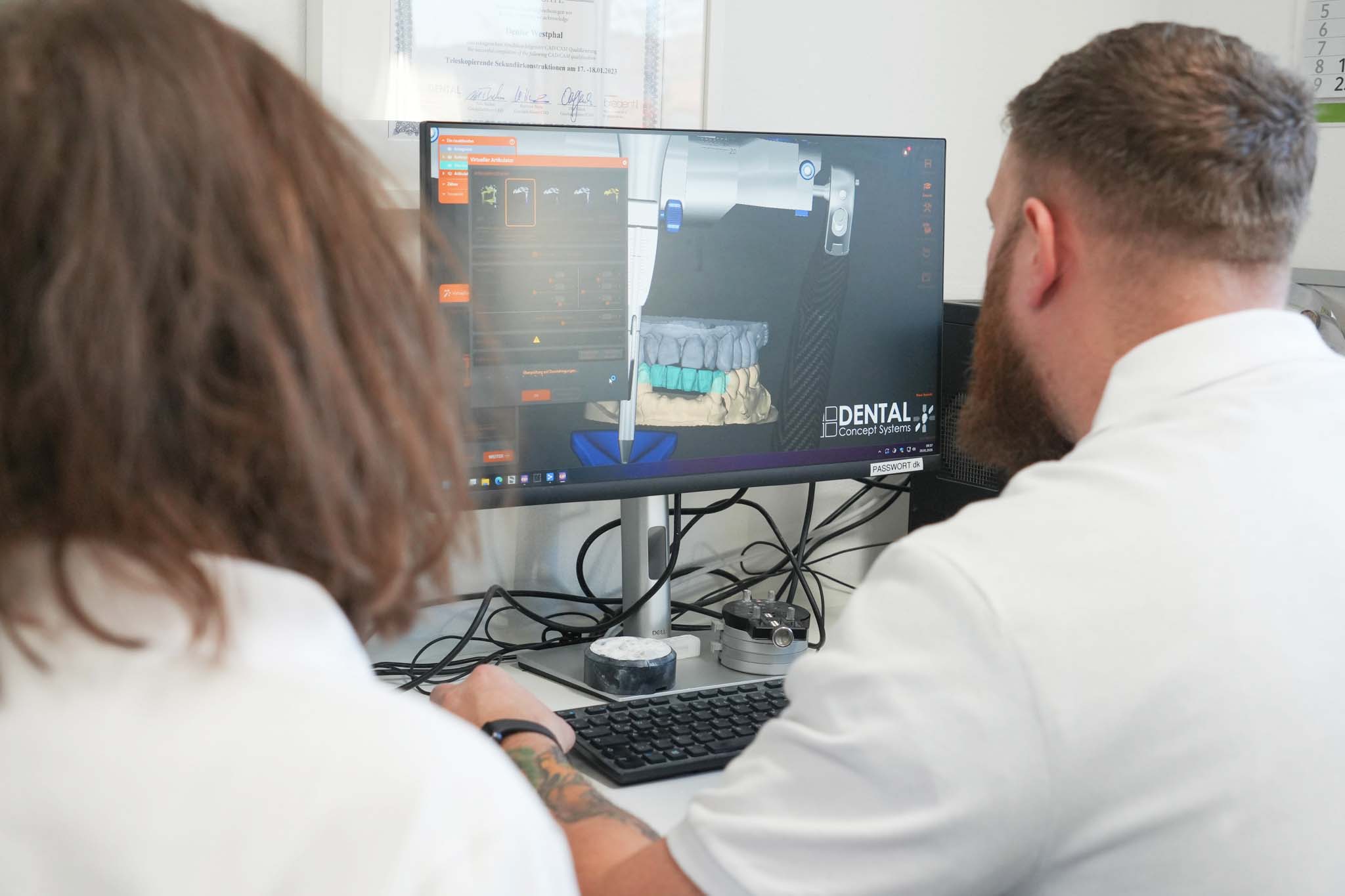 Zwei Mitarbeiter prüfen eine digitale Zahnkonstruktion am Computer