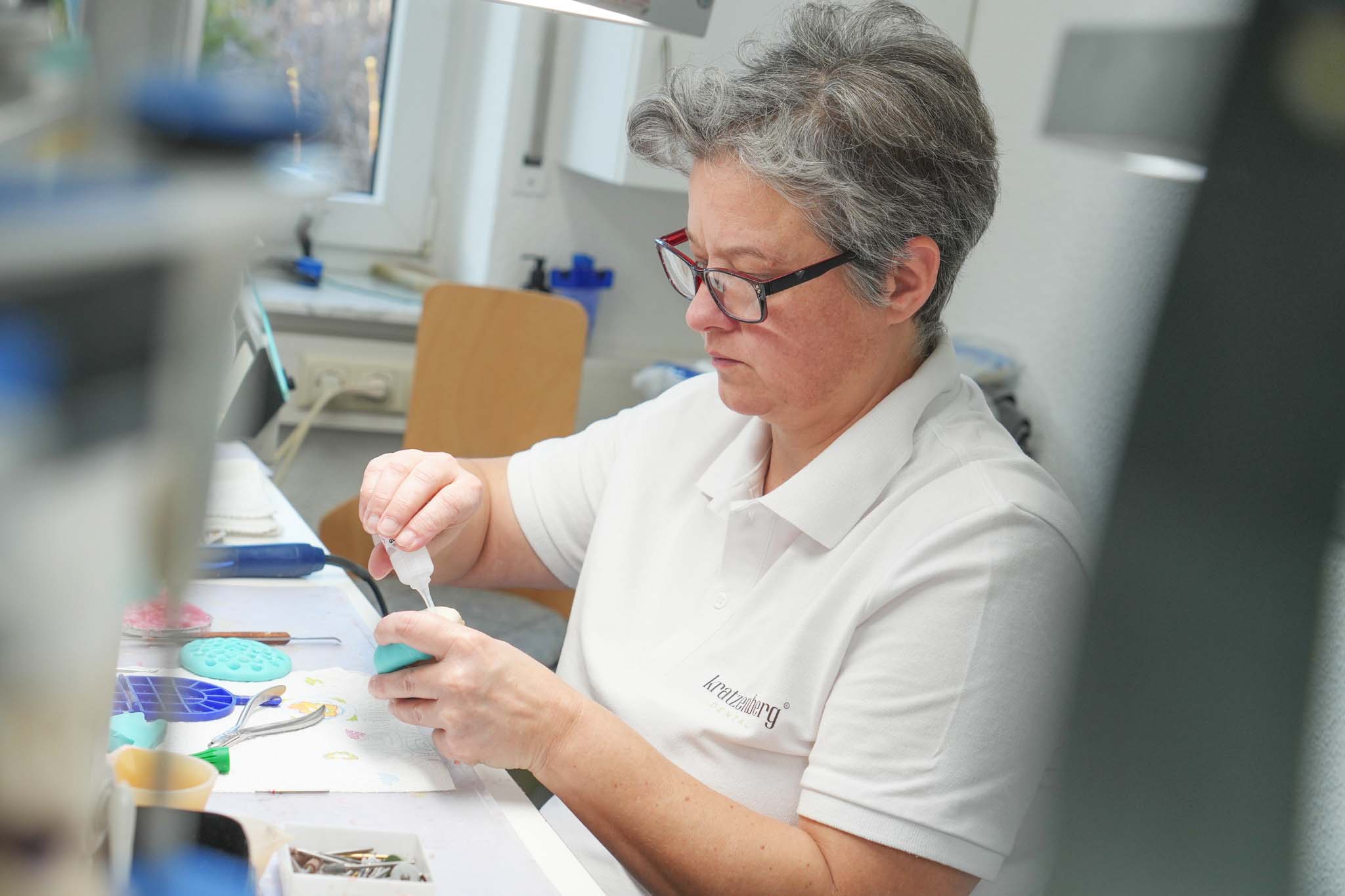 Mitarbeiterin bearbeitet ein Zahnmodell im Dentallabor