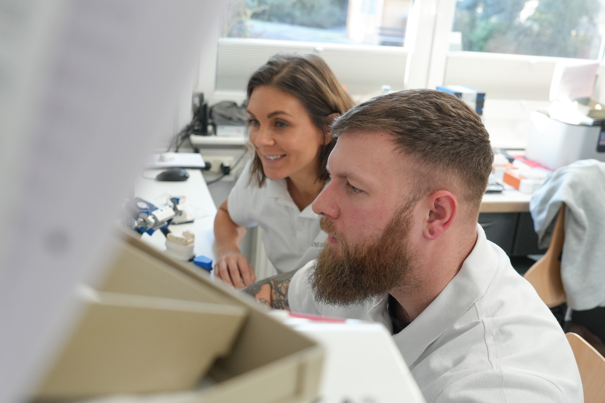 Zwei Mitarbeiter prüfen eine zahntechnische Arbeit im Dentallabor