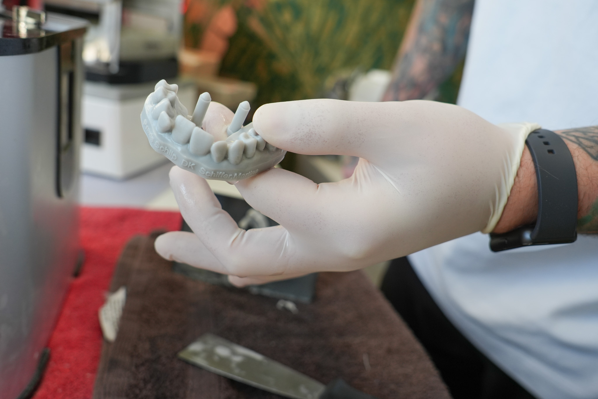 Gloved hand holds a 3D-printed dental model in the lab